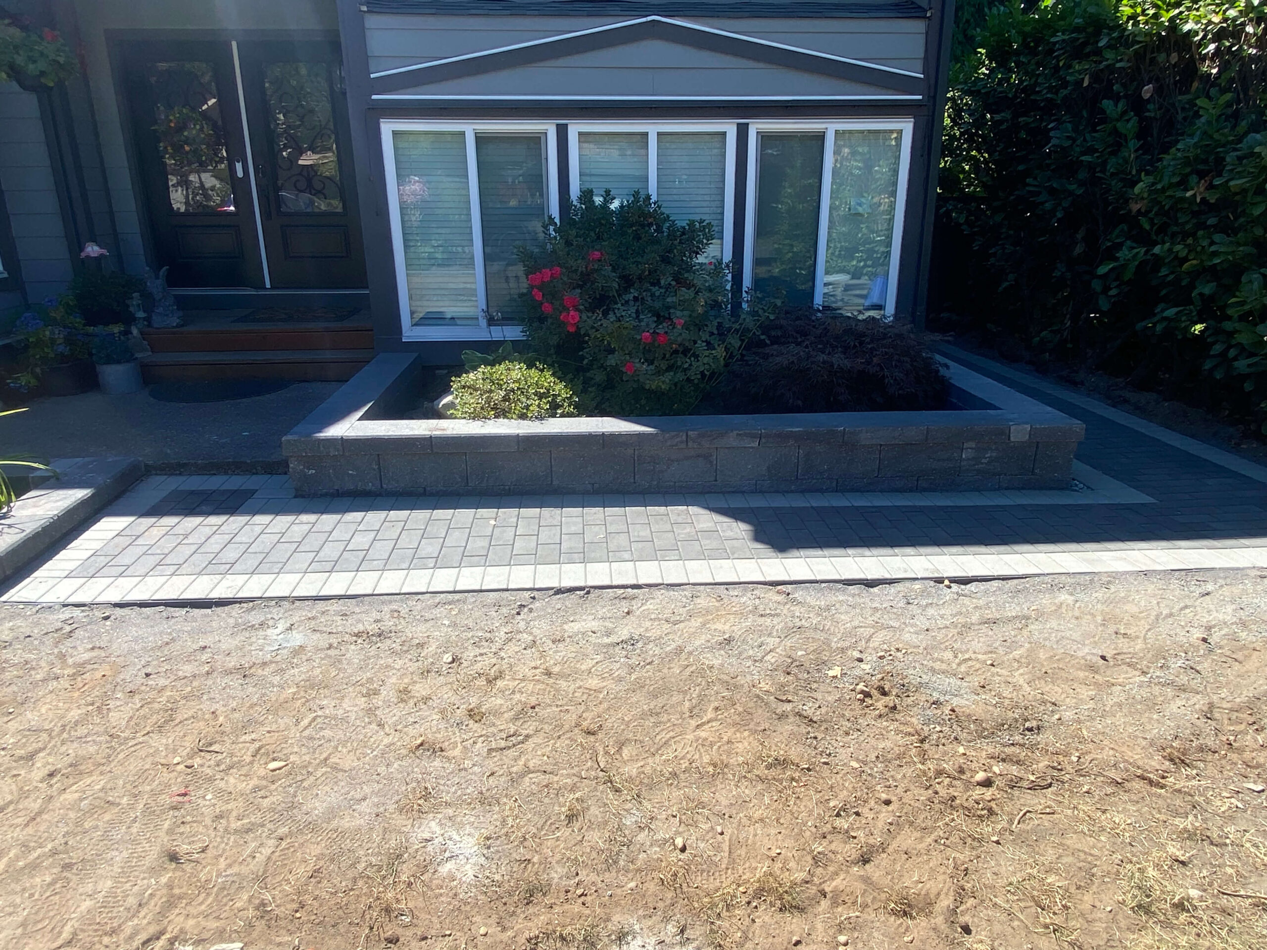 Front yard interlocking paver walkway and retaining wall planter in Calgary